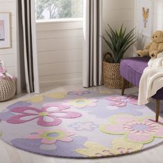 a child's room with a teddy bear and flower rug on the floor in front of a window