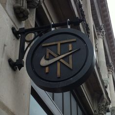 a sign hanging from the side of a building that says nike in gold and black