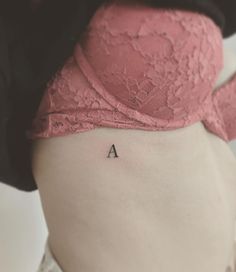 a woman's lower back tattoo with the letter a on her left side ribcage