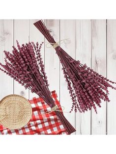 some dried flowers are sitting on a red and white checkered table cloth next to a wicker basket