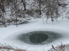 a hole in the snow surrounded by trees