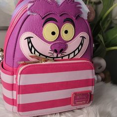 Loungefly X Disney Alice In Wonderland Cheshire Cat Mini Backpack Faux Leather Hand Wipe Clean. Imported. "We're All Mad Here." Mad About This Marvelous Disney Alice In Wonderland Cheshire Cat Mini-Backpack, That Is! Features: Zipped Closure, Front Zippered Pocket Closure, Adjustable Straps, Applique, Embroidery Detials, Enamel Zipper Pull, 2 Side Pockets, Glow-In-The-Dark Face, Matching Themed Lining, And Inside Pocket Approximate Dimensions - W: 9" X H: 12" X D: 4" Brand New Cute Standard Backpack For Theme Parks, Cute Standard Backpack For Theme Park, Playful Backpack For Theme Park, Disneyland Backpack, Loungefly Purse, Dark Face, Alice In Wonderland Cheshire Cat, Wonderland Cheshire Cat, We're All Mad Here