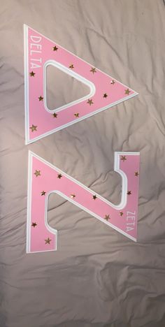 two pink and white triangle shaped signs sitting on top of a bed