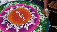 a person standing next to a colorful rangolite design on the ground with words welcome