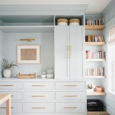 a room with white cabinets and shelves filled with books