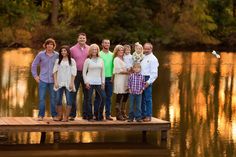 a group of people standing on a dock in front of a body of water at sunset