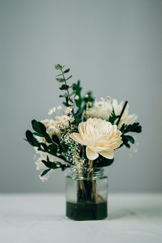 a vase filled with white flowers and greenery