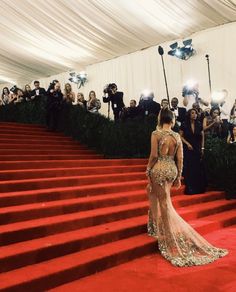 the back of a woman's dress at an event with people taking pictures behind her