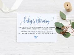 baby's library card with eucalyptus leaves and twine on white wooden table next to ribbon