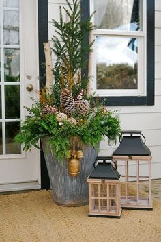 a potted plant with pine cones and greenery in front of a house