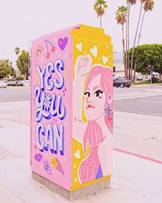 there is a pink and yellow box on the side of the street that says yes you can