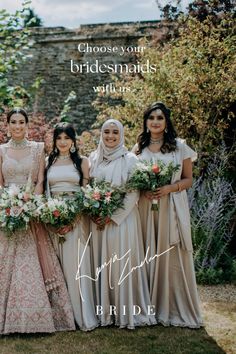 a group of women standing next to each other in front of a stone wall and trees