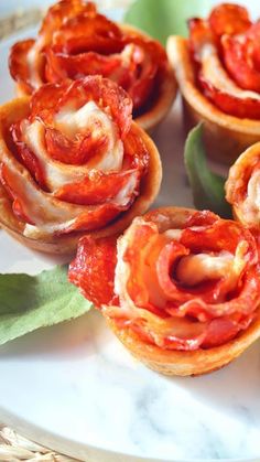 small appetizers are arranged on a plate with green leafy stems and leaves