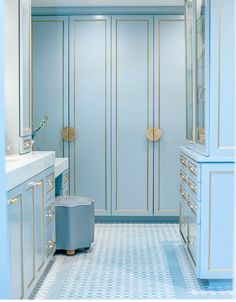 a blue and white bathroom with gold trim on the doors, drawers, and cabinets