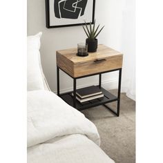 a nightstand with a plant on it next to a bed