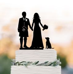 a wedding cake topper with a bride and groom holding hands next to a dog