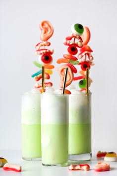 two glasses filled with green liquid and candy sticks