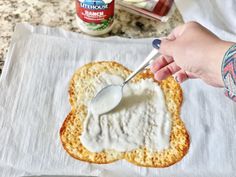 a person spreading cream on top of a piece of bread with a spoon in it