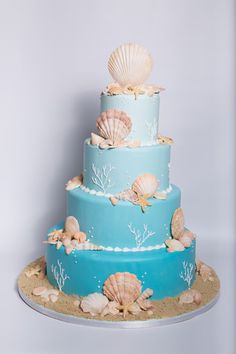 a three tiered blue cake with seashells on it