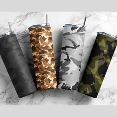 four different colored camo travel tumbles on a marble surface