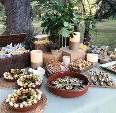 a table topped with lots of food next to a forest filled with trees and bushes