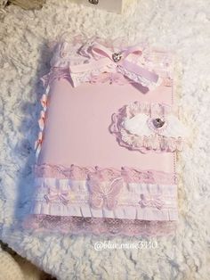 a pink book with lace and bows on it sitting on a white furnishing