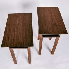 two wooden tables sitting next to each other on a white surface in front of a plain background