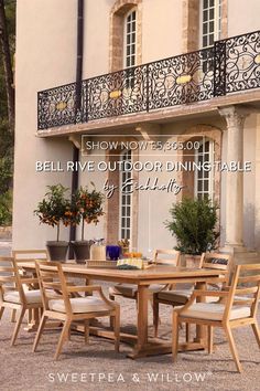 an outdoor dining table and chairs in front of a building