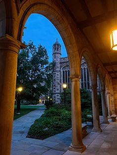 an archway leading to a building with a clock tower in the background at night time