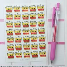 a pink pen sitting on top of a notebook next to a sticker with cupcakes