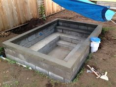 a concrete pit in the middle of a yard with a blue tarp over it