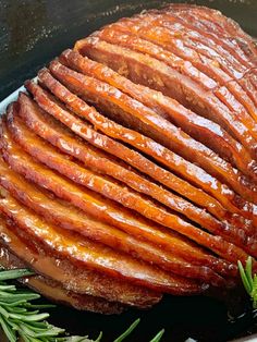 sliced ham in a skillet with rosemary sprigs on the side, ready to be cooked