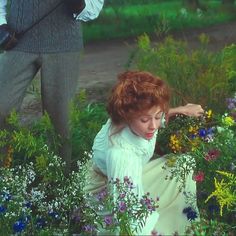 a woman kneeling down in a field of flowers