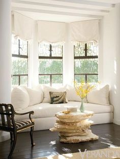 a living room filled with white furniture and lots of windows in it's walls