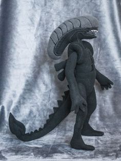 a toy godzilla is posed on a gray background