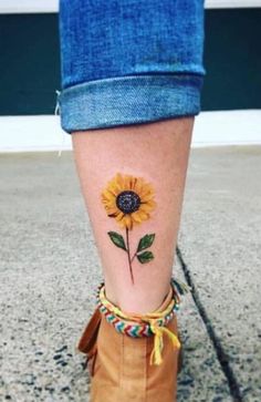 a woman's foot with a sunflower tattoo on the side of her leg