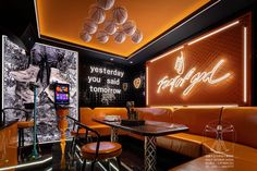 the interior of a restaurant with orange booths and neon lights on the walls, along with artwork