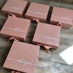 six pink boxes with names on them sitting on a wooden floor next to each other