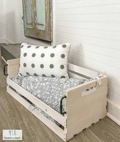 a wooden day bed with pillows on top of it and a mirror above the bed