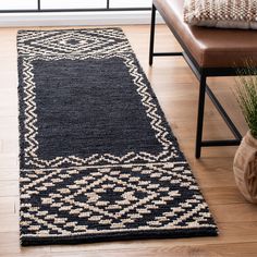 a black and white rug on the floor next to a chair with a plant in it