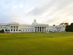 a large white building sitting on top of a lush green field