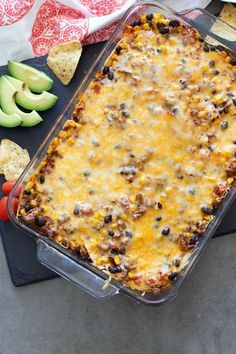 an enchilada casserole with tortilla chips and avocados