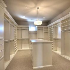 an empty walk - in closet with white cabinets and drawers on the walls, along with a bar