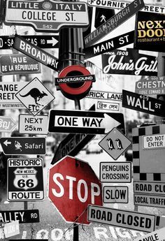 a bunch of street signs that are on the side of a road in black and white