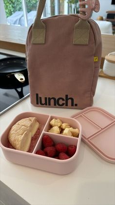 lunch box with sandwich, fruit and muffins in front of lunch bag on counter