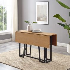 a wooden table with two metal legs and a bowl on it, in front of a window