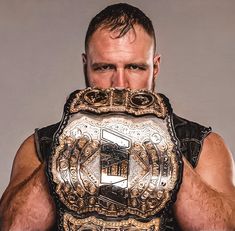 a man holding up a wrestling belt in front of his face and looking at the camera