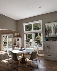 a dining room table and chairs in front of large windows