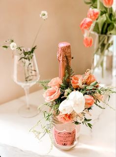 a vase filled with flowers next to a wine bottle