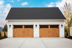 two brown garage doors are open in front of a white house